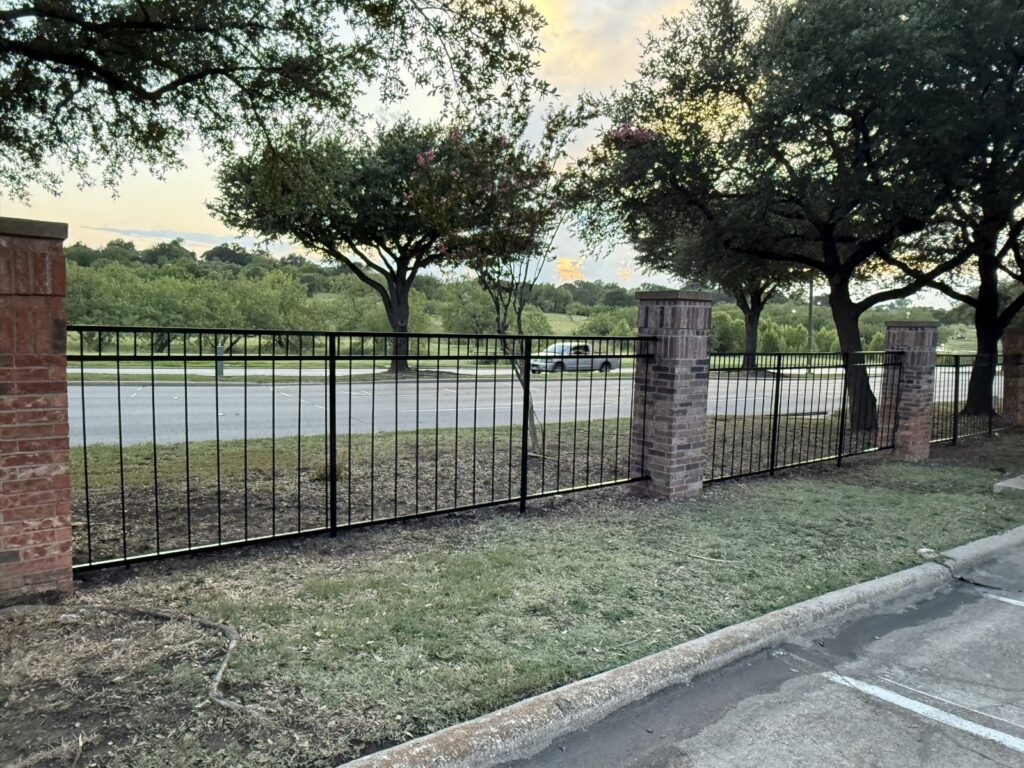 Black ornamental iron fence with brick columns installed by Fence Guy