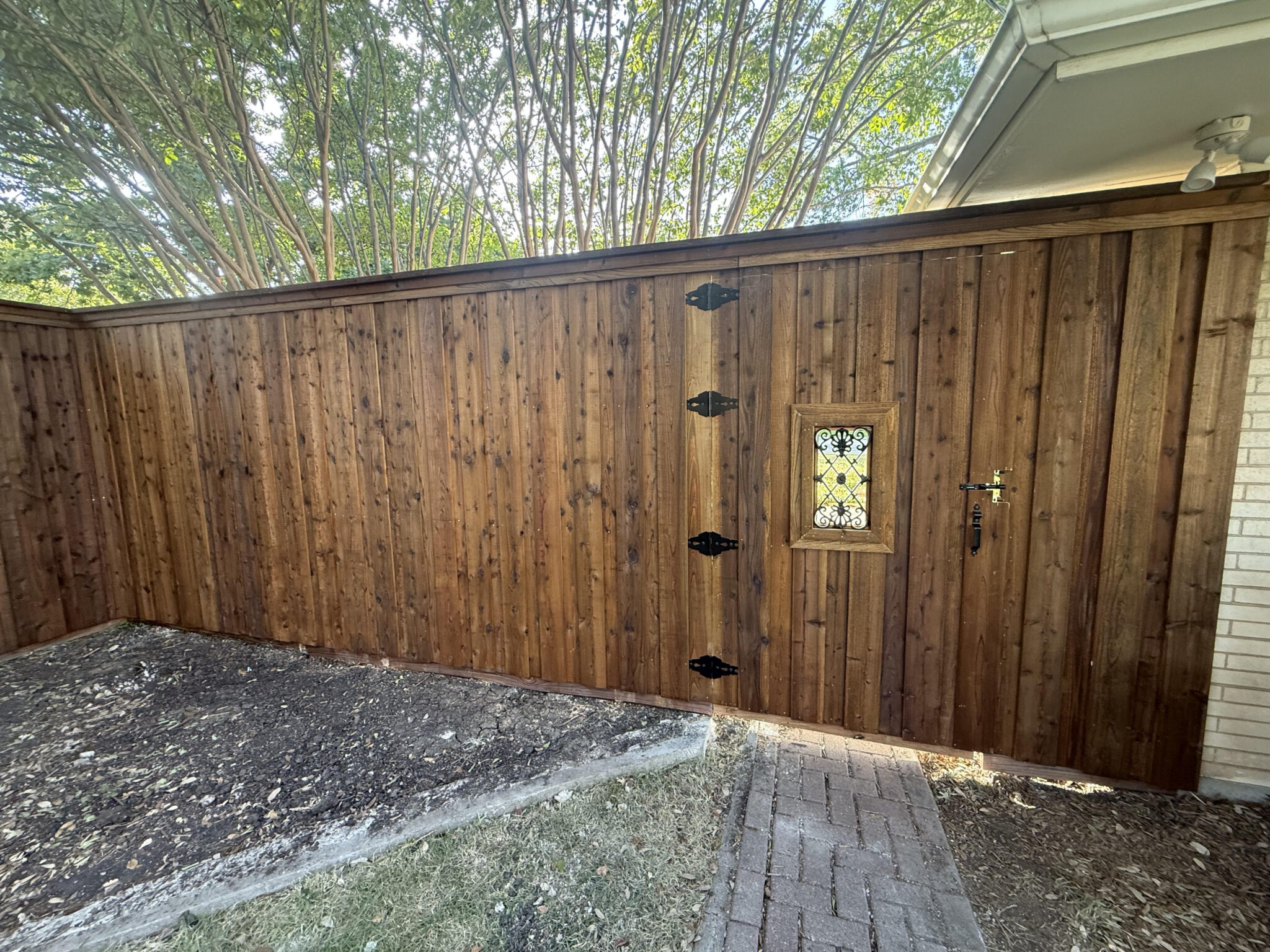 Stained cedar privacy fence with decorative iron-window gate installed by Fence Guy in DFW and North Texas