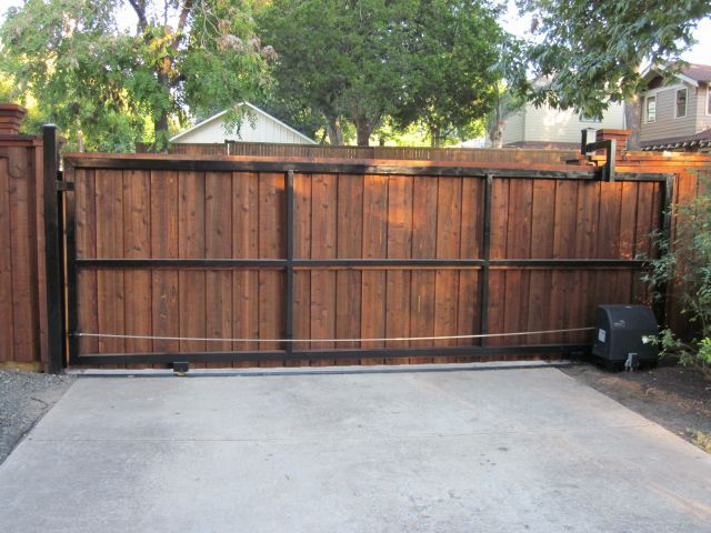 Automatic cedar V-track sliding driveway gate installed by Fence Guy